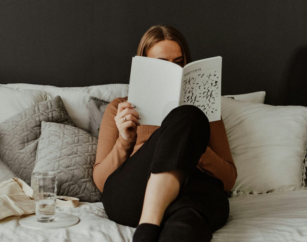 Frau über Identität lesend im Bett, gemütliche Atmosphäre.