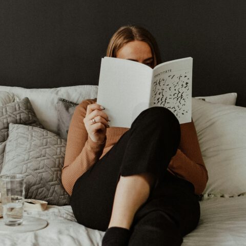 Frau über Identität lesend im Bett, gemütliche Atmosphäre.