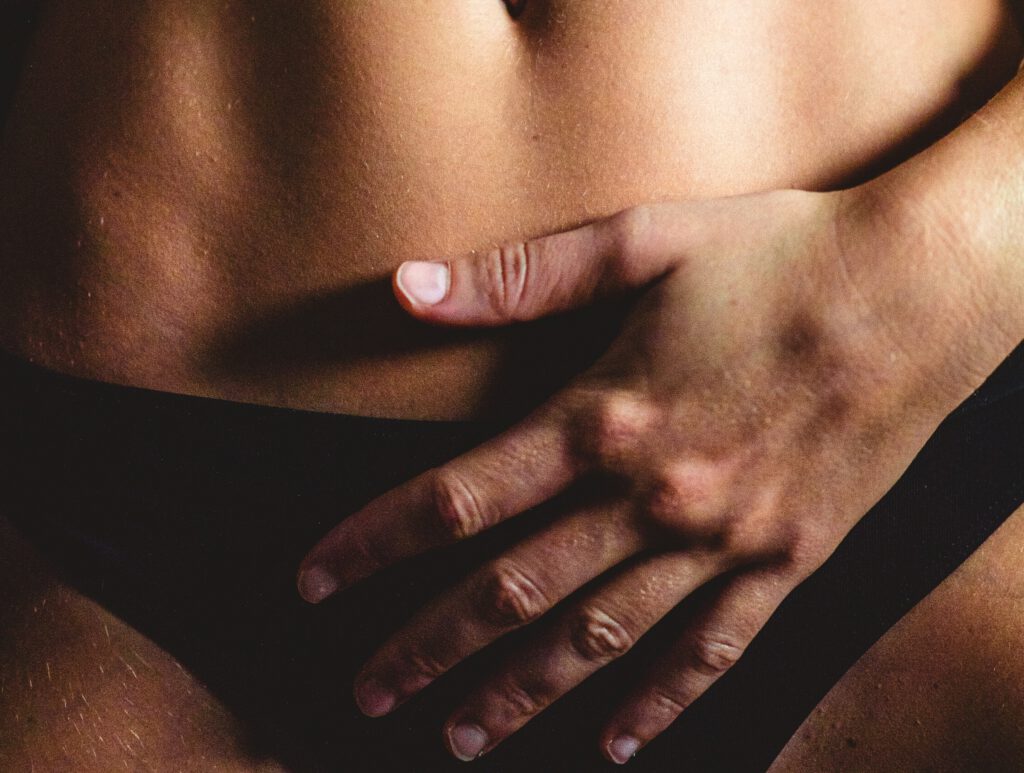 Sanfte, achtsame Berührung einer Frau auf dem Unterbauch – Intimmassage und bewusste Selbstwahrnehmung