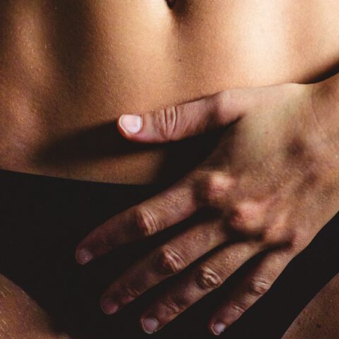 Sanfte, achtsame Berührung einer Frau auf dem Unterbauch – Intimmassage und bewusste Selbstwahrnehmung